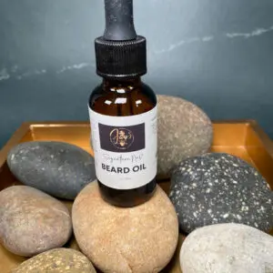 A bottle of beard oil surrounded by smooth stones.
