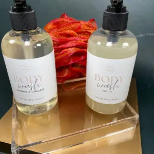 Two bottles of hand soap on a clear acrylic stand with dried flowers in the background.