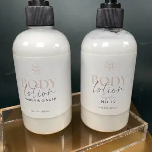 Two white bottles of Body Color hand and body lotion with black pumps.