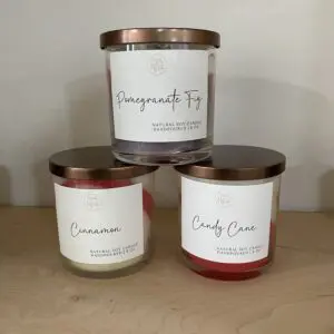 Three scented candles with copper lids on a wooden surface.