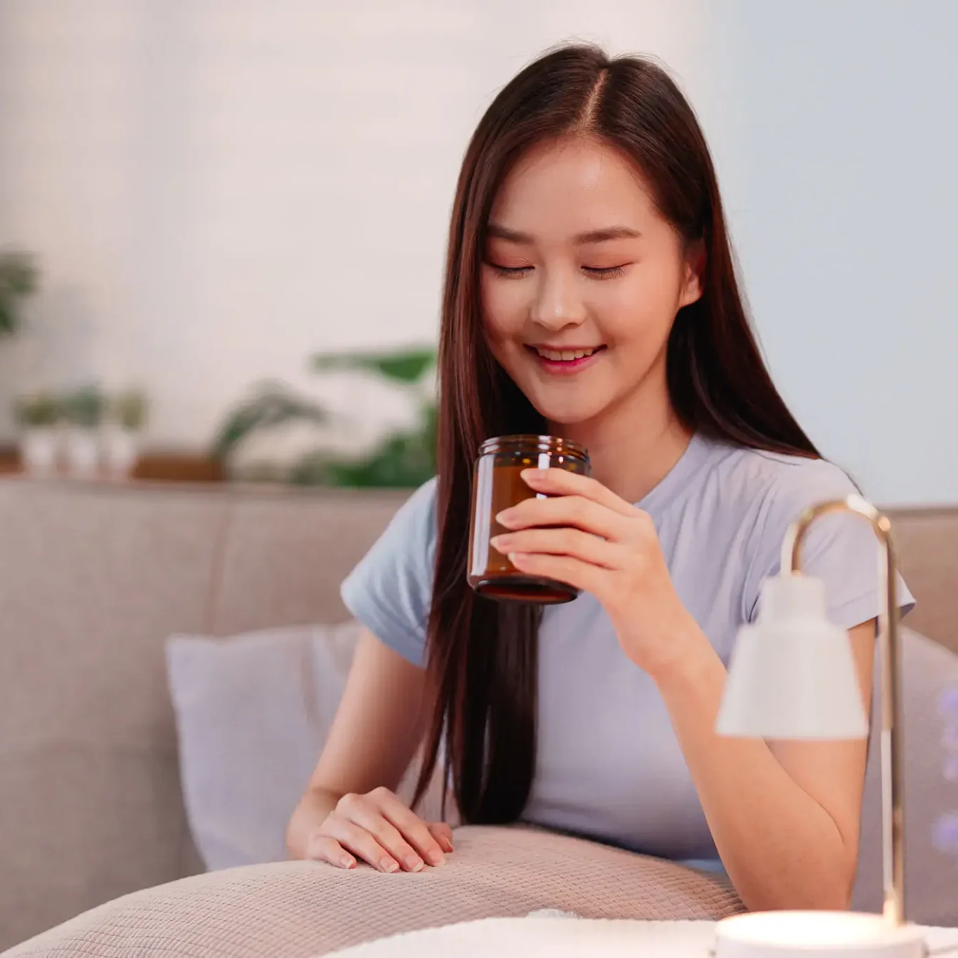 Young woman happily drinking coffee while sitting on a couch.